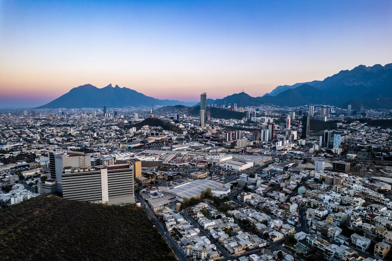 gallery-04 Capture of Monterrey's skyline with high-rise buildings and mountains at dusk.