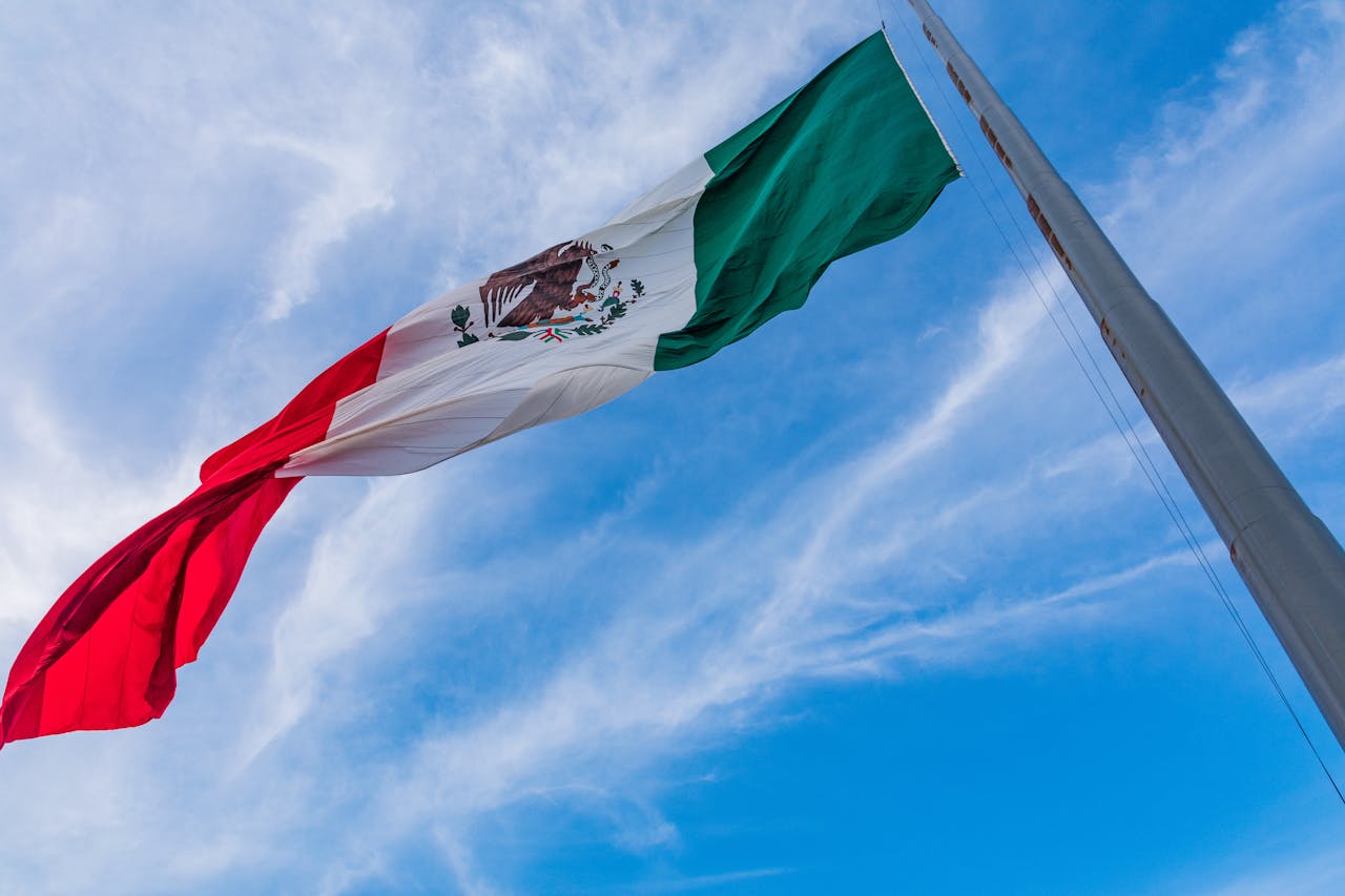 Vibrant Mexican flag waving against a bright blue sky in Monterrey, capturing national pride.