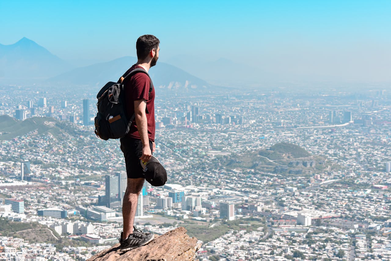 A man standing on a rock, overlooking the scenic cityscape of Monterrey, México.